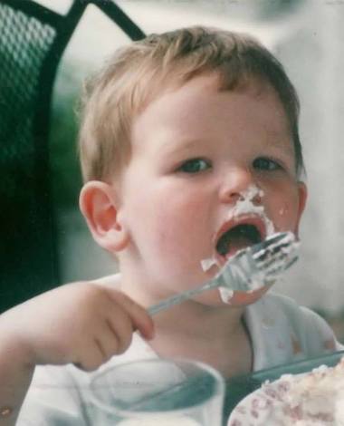 Baby Martin, covered in frosting, licking frosting covered fork