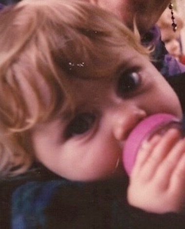 Small blonde Liv holding bottle while staring into camera